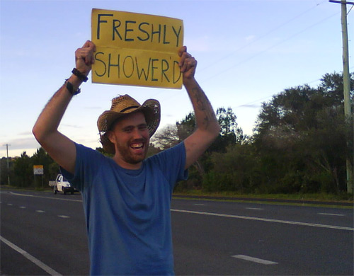 Hitchhiker with a sign saying "Freshly Shower'd"